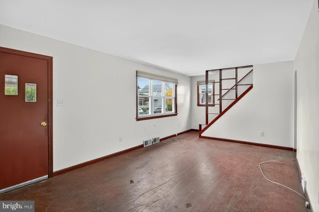 a view of an empty room with wooden floor and stairs