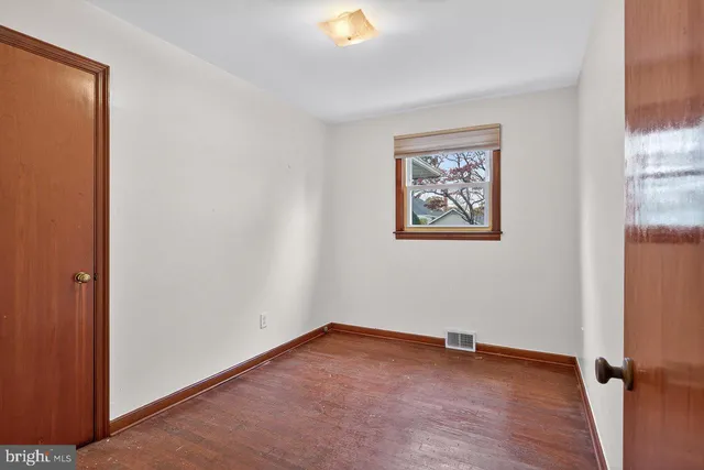 an empty room with a window and wooden floor