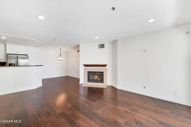 a view of an empty room with wooden floor fireplace and a window
