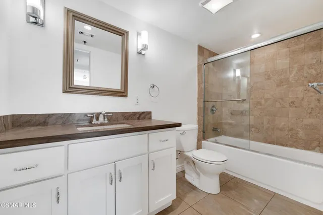 a bathroom with a granite countertop sink a toilet and shower
