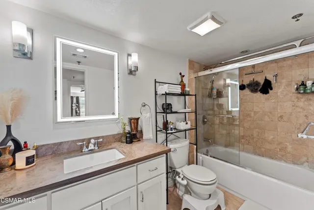 a bathroom with a granite countertop sink toilet mirror and shower