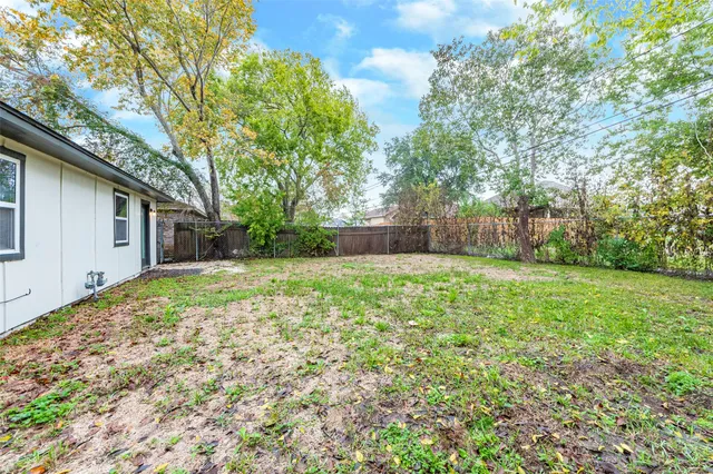 a backyard of a house with large trees and plants