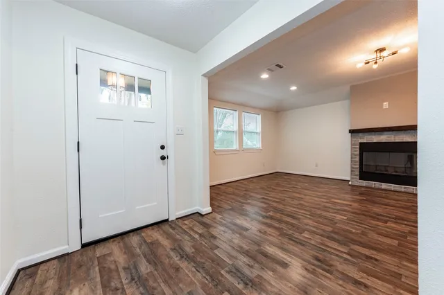 an empty room with wooden floor fireplace and windows