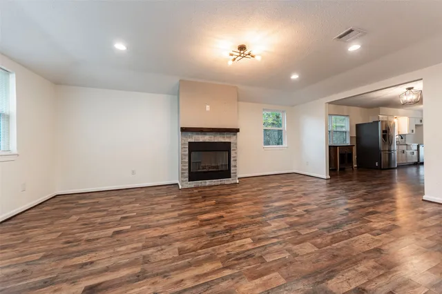 an empty room with wooden floor fireplace and windows