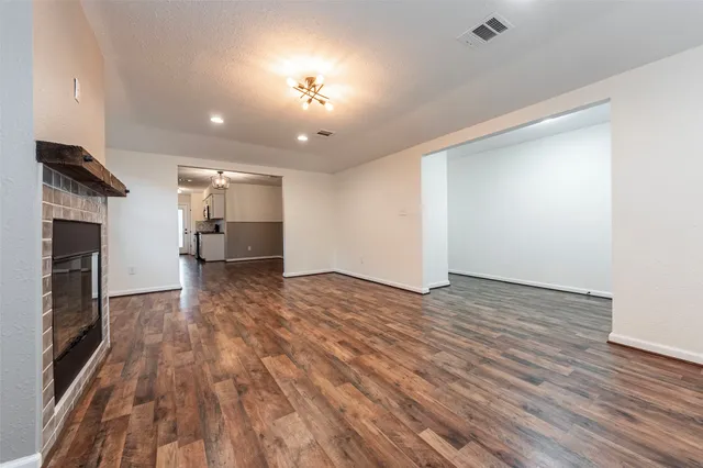 an empty room with wooden floor fireplace and windows