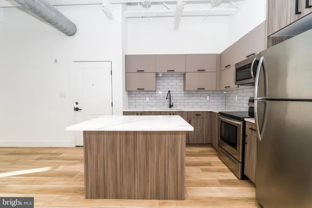 a kitchen with stainless steel appliances a sink a stove a refrigerator and cabinets