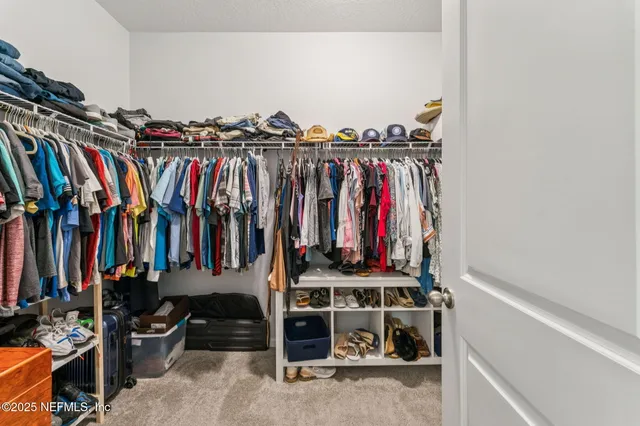 a view of walk in closet with clothes and shoes