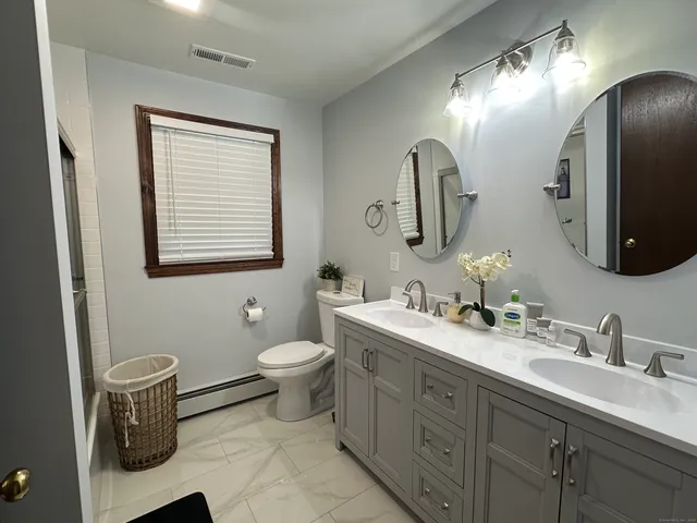a bathroom with a toilet sink double vanity and mirror