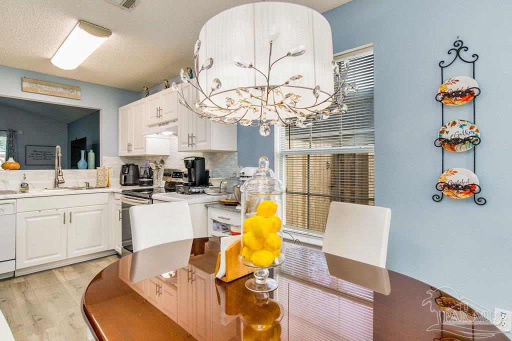 2466 Redoubt Avenue Pensacola, FL 32507 - Photo 8 of 27 a living room with furniture a chandelier and kitchen view