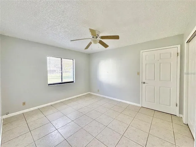 an empty room with windows and fan
