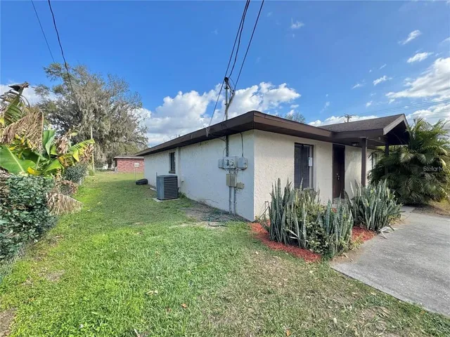 a view of a house with a big yard potted plants and large tree