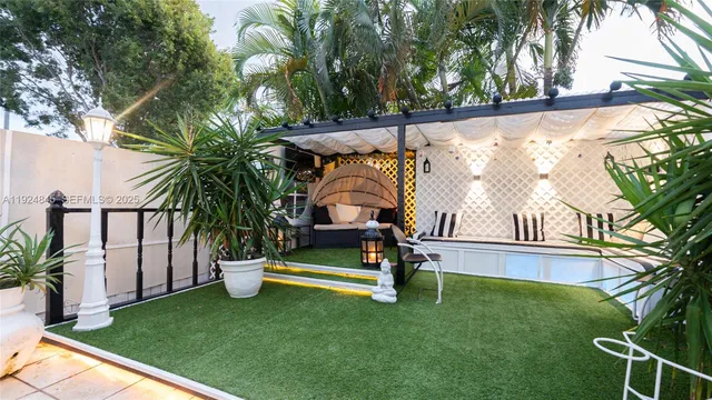 a backyard of a house with table and chairs plants and a large tree