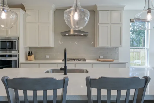 a kitchen with stainless steel appliances granite countertop a dining table chairs a microwave a refrigerator and cabinets