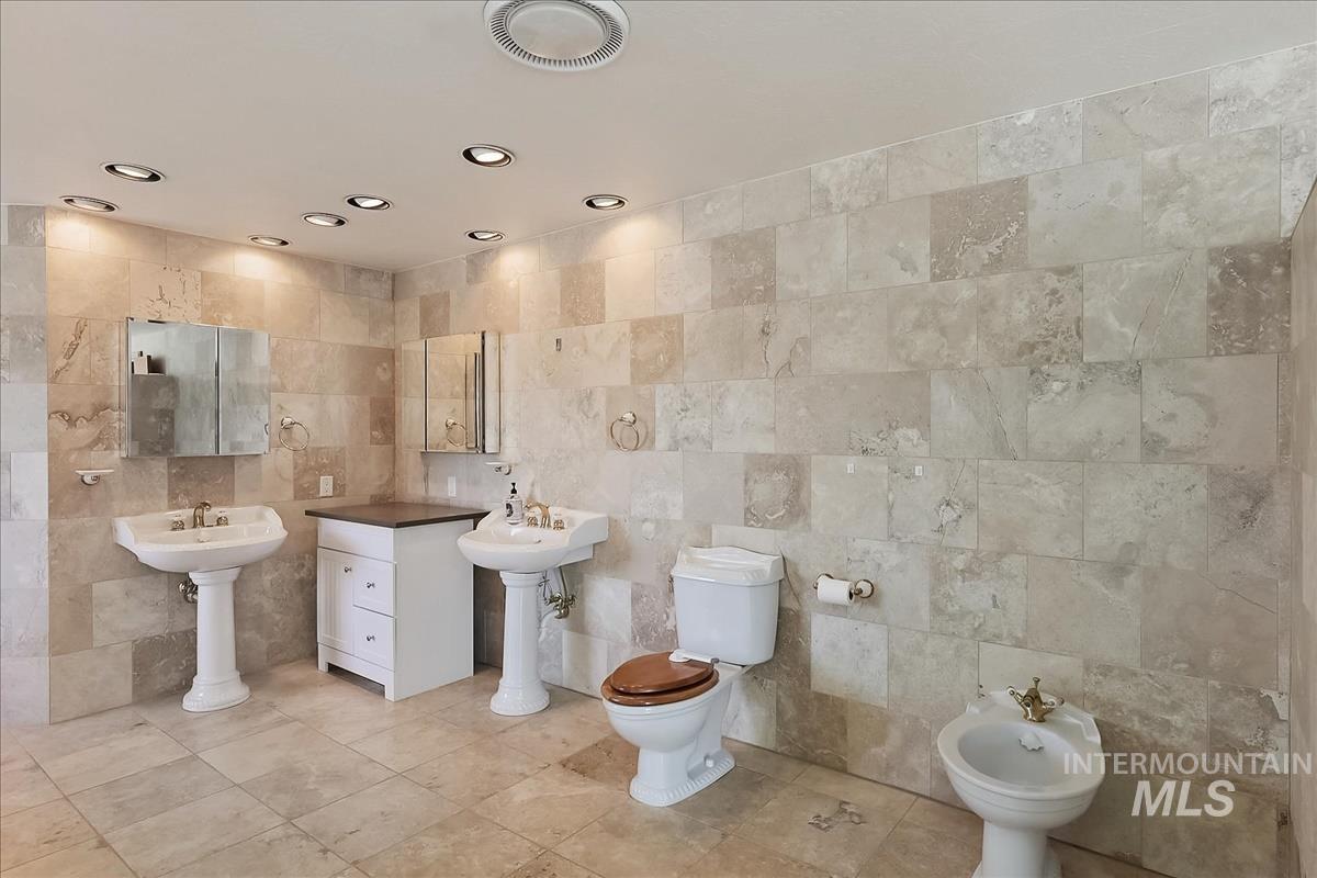 2804 West Sunrise Rim Road Boise, ID 83705 - Photo 38 of 50 Spacious bathroom featuring expansive floor and wall tile, two pedestal sinks, recessed lighting, and a bidet