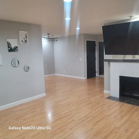 a view of a livingroom with wooden floor and a fireplace