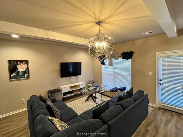 a living room with furniture a chandelier and a flat screen tv