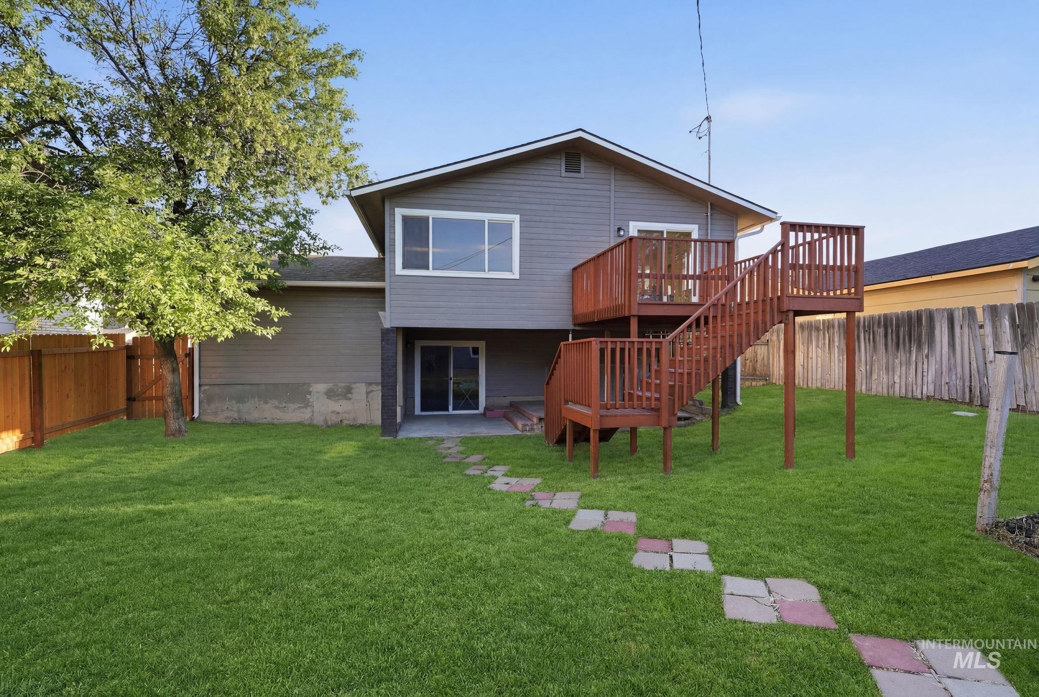 1990 Panama Street Boise, ID 83705 - Photo 47 of 50 Expansive backyard with a manicured lawn, featuring a multi-level wood deck with stairs, a ground-level patio, and a stone path