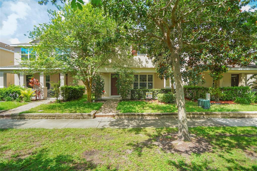 a view of house in front of a big yard with large trees