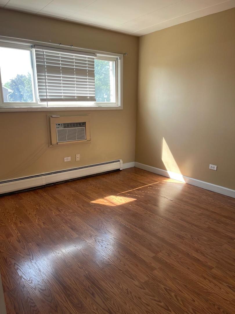 1000 South Lorraine Road, Unit 214 Wheaton, IL 60189 - Photo 3 of 12 an empty room with wooden floor and windows