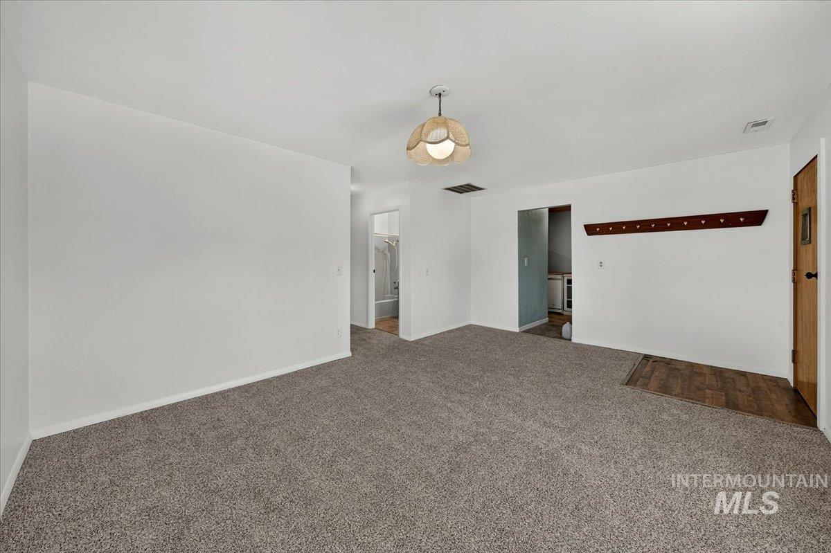 2160 South Five Mile Road Boise, ID 83709 - Photo 27 of 41 Spacious room featuring new carpeting, a decorative ceiling light fixture, a light wood-finish entry door, a built-in wooden coat rack, and a wood-finish flooring entry area