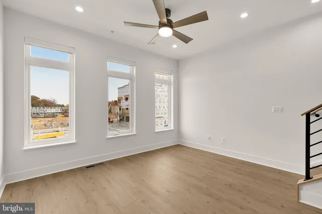a view of an empty room with wooden floor and ceiling fan