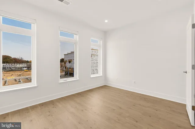 an empty room with wooden floor cabinet and windows