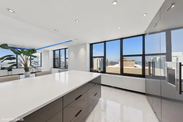 a large white kitchen with large windows and refrigerator