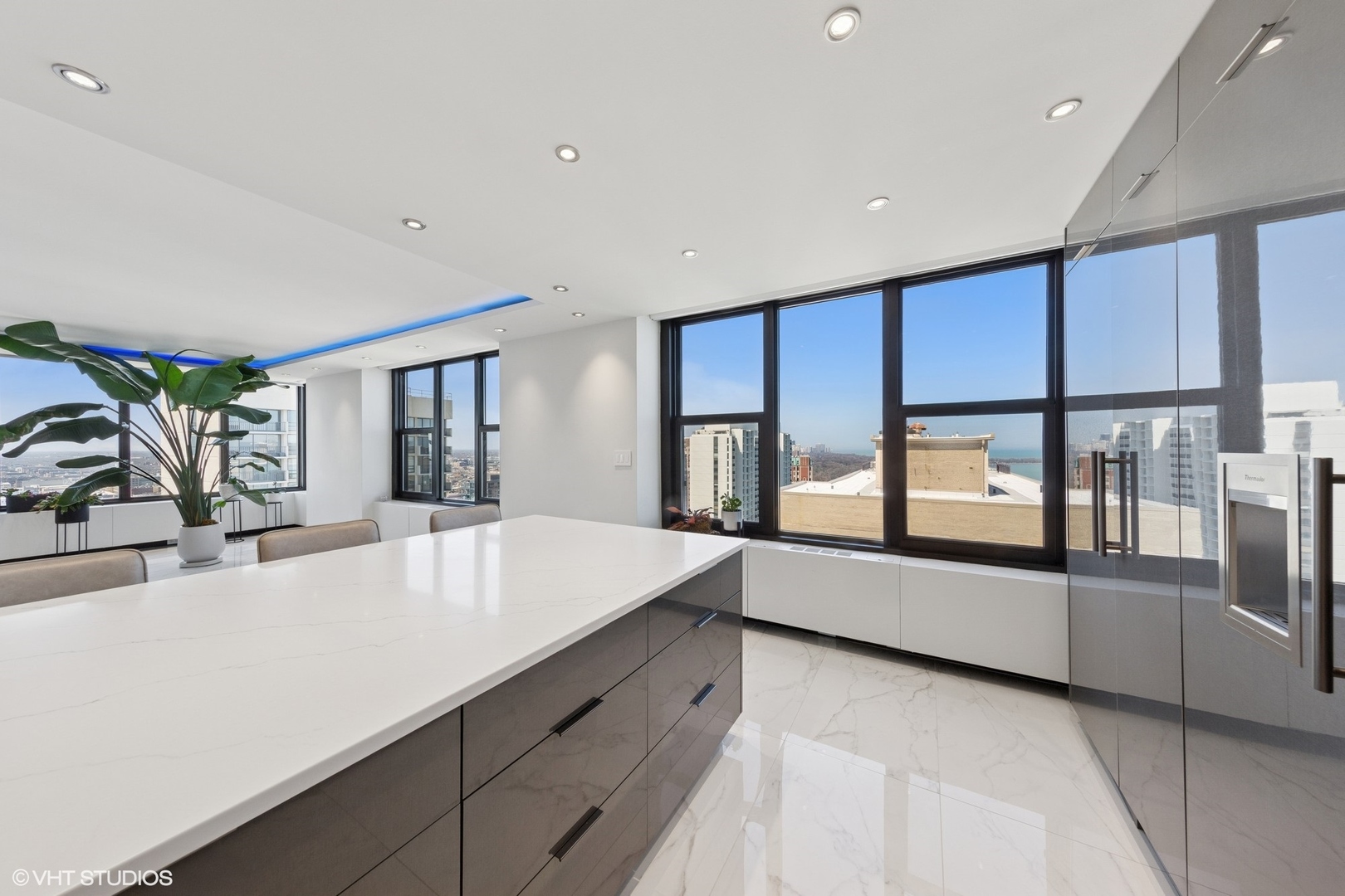 3150 North Lake Shore Drive, Unit 27F Chicago, IL 60657 - Photo 13 of 31 a large white kitchen with large windows and refrigerator