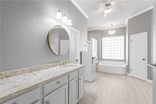 a spacious bathroom with a granite countertop double vanity sink a mirror and a bathtub