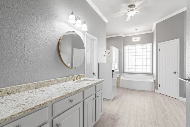 a spacious bathroom with a granite countertop double vanity sink a mirror and a bathtub