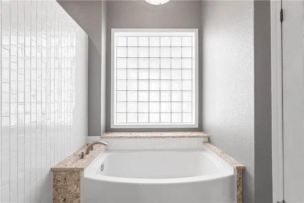 a white bath tub sitting in a bathroom next to a window