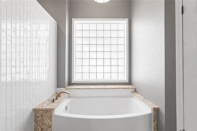 a white bath tub sitting in a bathroom next to a window