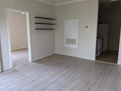 an empty room with wooden floor cabinet and windows