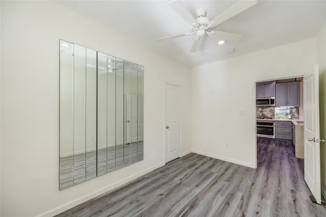 a view of a room with wooden floor and a ceiling fan