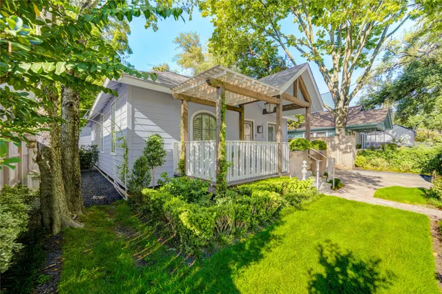 a view of a white house with a big yard and potted plants and large tree