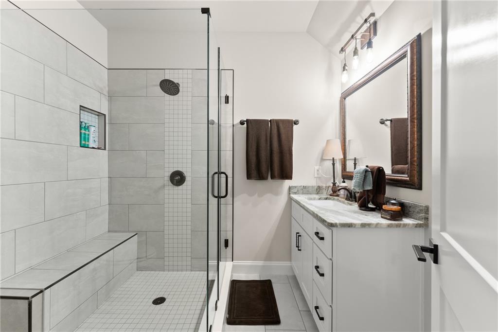 5431 Mayflower Court Gainesville, GA 30504 - Photo 41 of 64 a bathroom with a granite countertop sink a mirror a shower and vanity