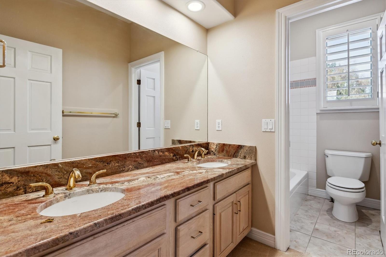 72 Falcon Hills Drive Highlands Ranch, CO 80126 - Photo 31 of 49 a bathroom with a granite countertop sink a large mirror and a toilet