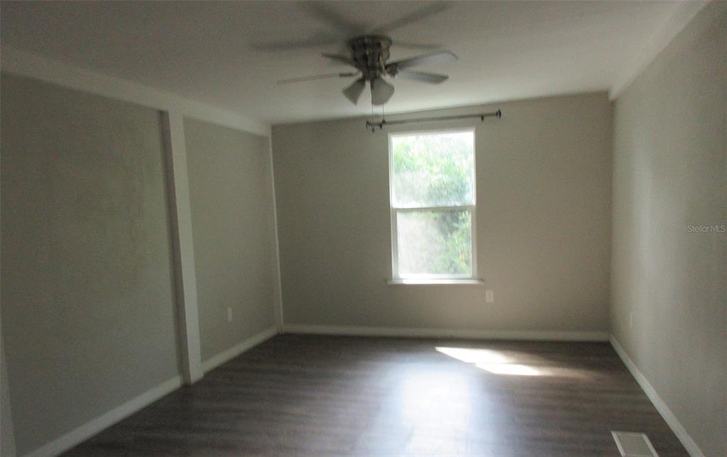 214 West Dade Avenue Bushnell, FL 33513 - Photo 10 of 13 an empty room with wooden floor chandelier fan and windows
