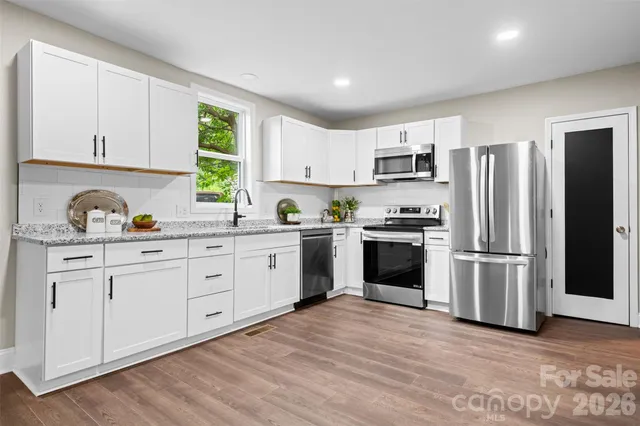 a kitchen with granite countertop white cabinets and stainless steel appliances