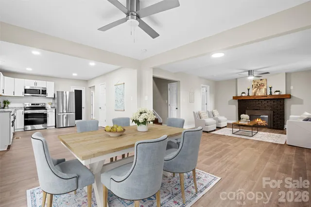 a view of a dining room with furniture a fireplace and wooden floor
