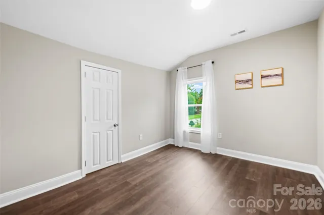 an empty room with wooden floor and window