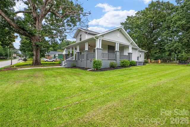 a view of a house next to a big yard with large trees