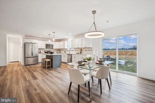 a living room with furniture a kitchen island with wooden floor and a chandelier