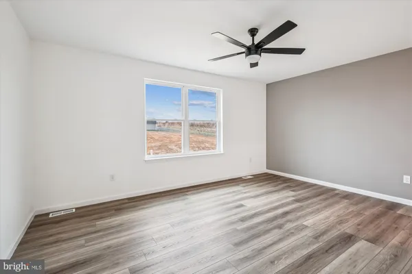 a view of a room with wooden floor and a ceiling fan