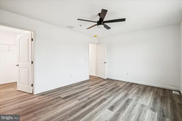 a view of empty room with wooden floor and ceiling fan
