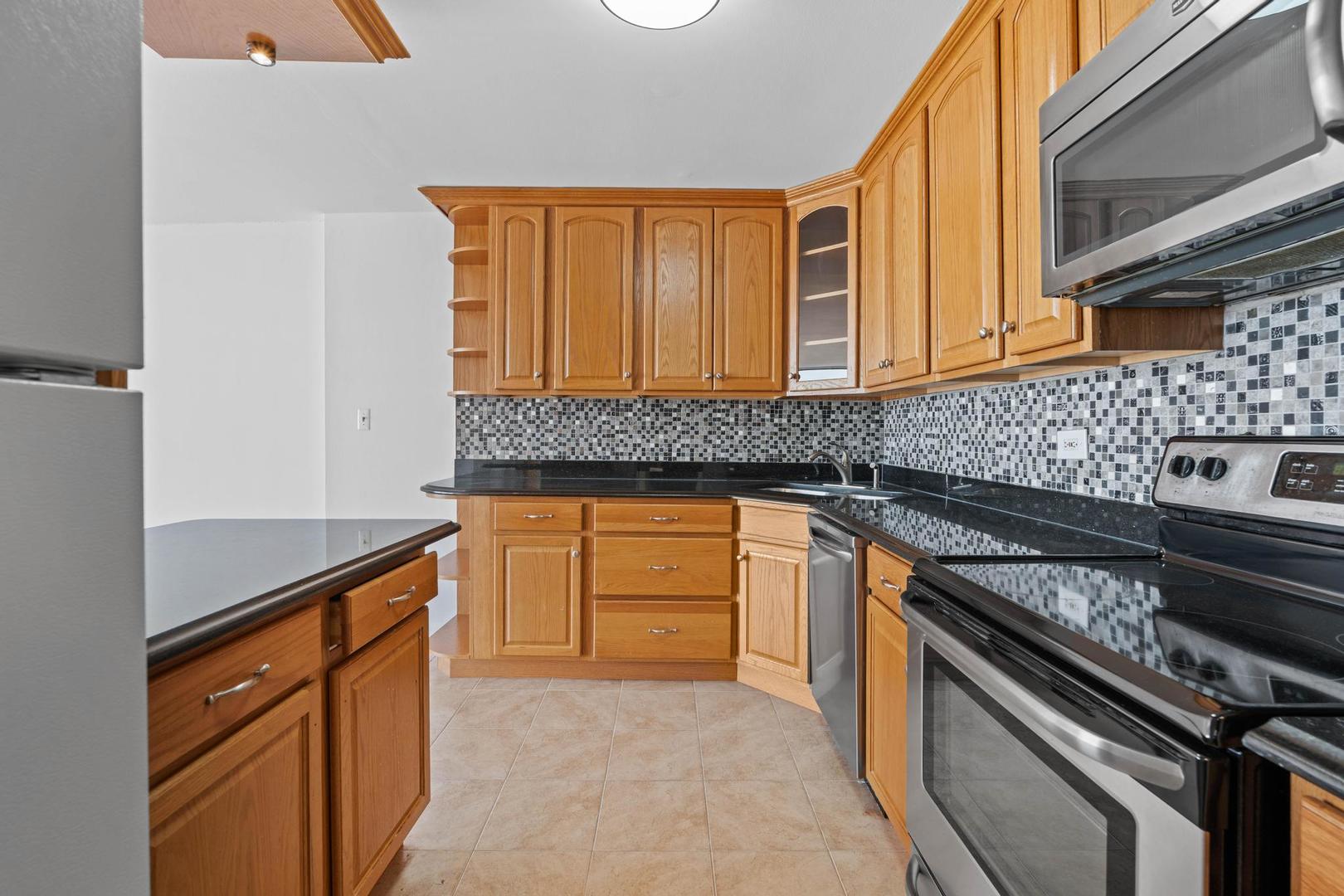 5455 North Sheridan Road, Unit 3611 Chicago, IL 60640 - Photo 11 of 18 a kitchen with granite countertop stainless steel appliances and wooden cabinets