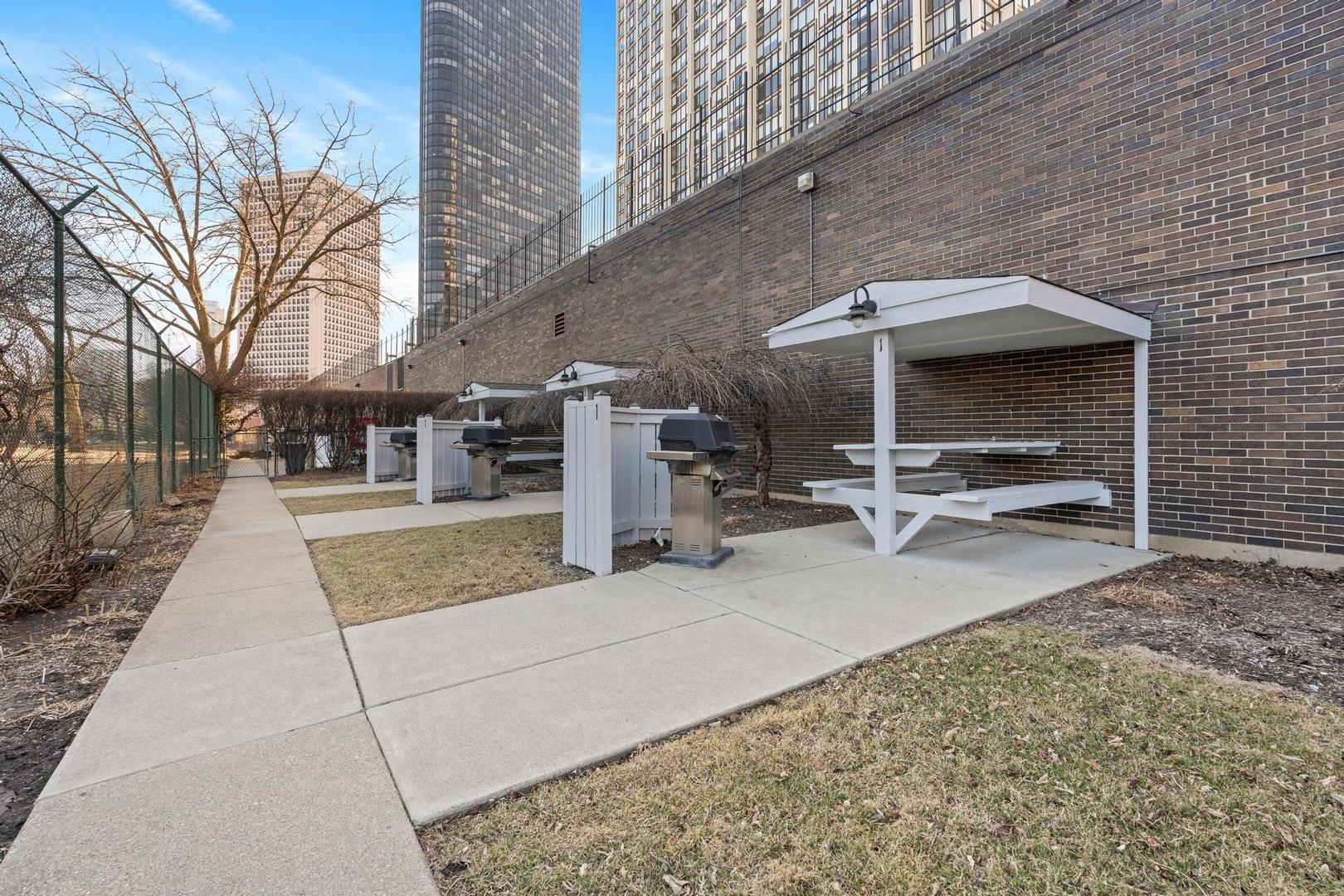 5455 North Sheridan Road, Unit 3611 Chicago, IL 60640 - Photo 18 of 18 a view of a patio with table and chairs a barbeque with wooden fence