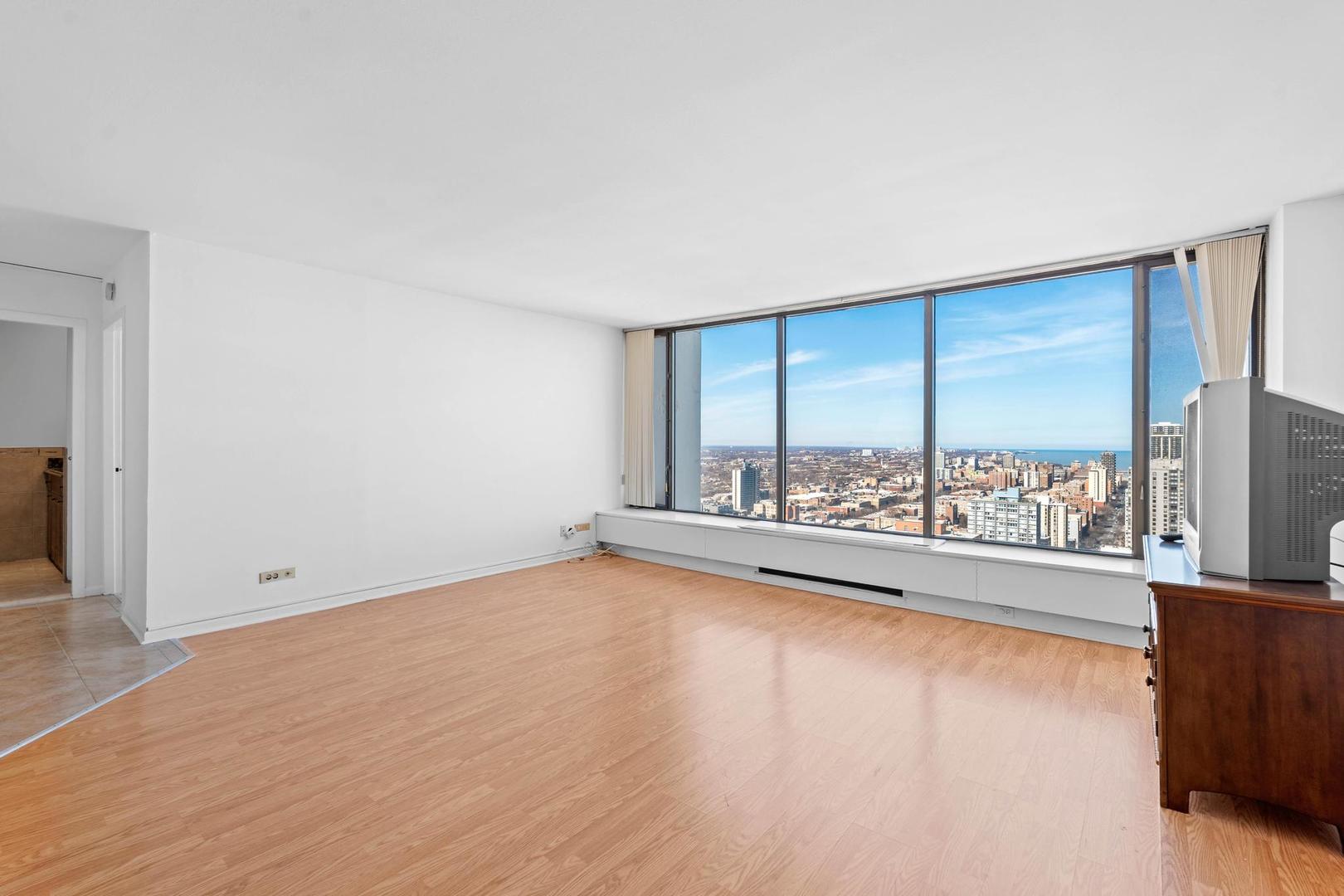 5455 North Sheridan Road, Unit 3611 Chicago, IL 60640 - Photo 9 of 18 an empty room with wooden floor and windows