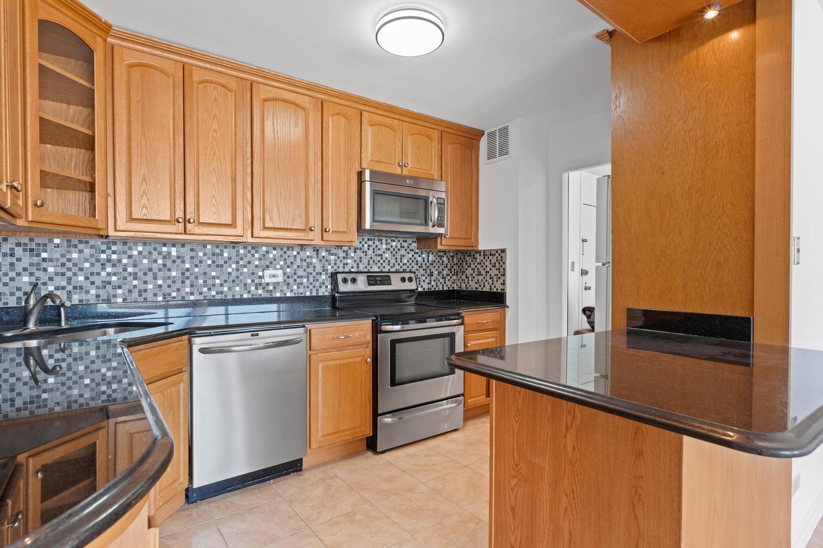 5455 North Sheridan Road, Unit 3611 Chicago, IL 60640 - Photo 10 of 18 a kitchen with stainless steel appliances granite countertop a stove a sink and a microwave