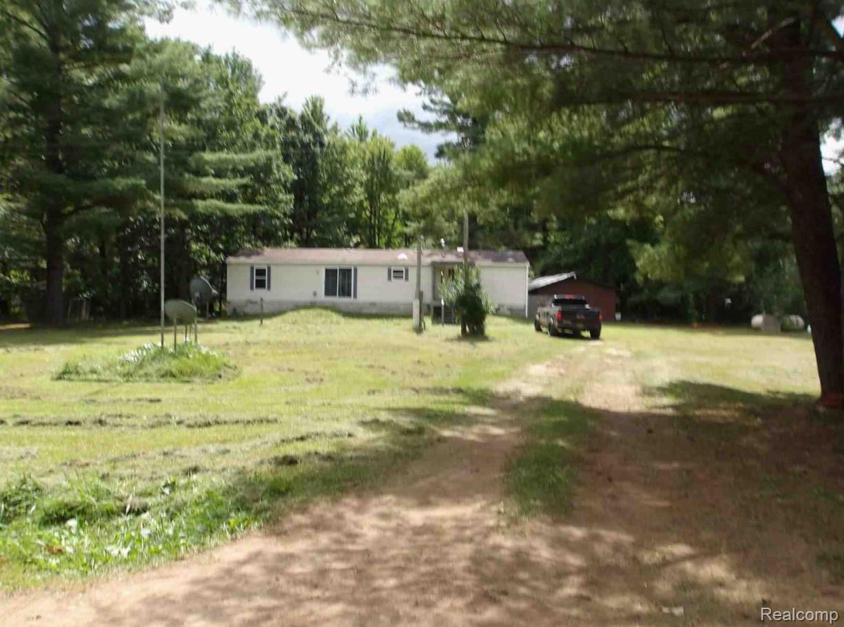 5727 West Huckleberry Road Shepherd, MI 48883 - Photo 1 of 1 View of front of home featuring a front lawn and view of wooded area